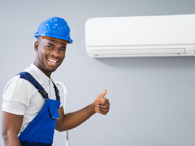 Technician Giving A Thumbs Up In Front Of A Mini-Split Heat Pump