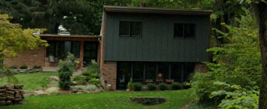 dark green home with lots of greenery around it