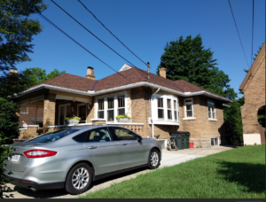 Permanent Load Reduction case study home exterior showing brick bungalow used for blower door and duct leakage testing